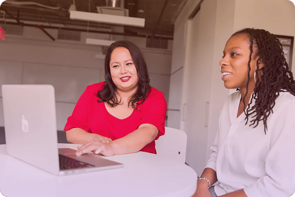 Mulheres reunidas em torno de um computador